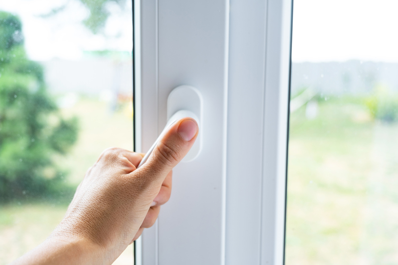 the hand holds the handle of a plastic double glazed window, clo